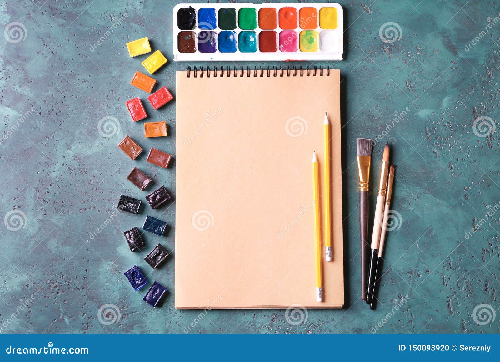 Notebook with Watercolors and Paint Brushes on Table Stock Photo