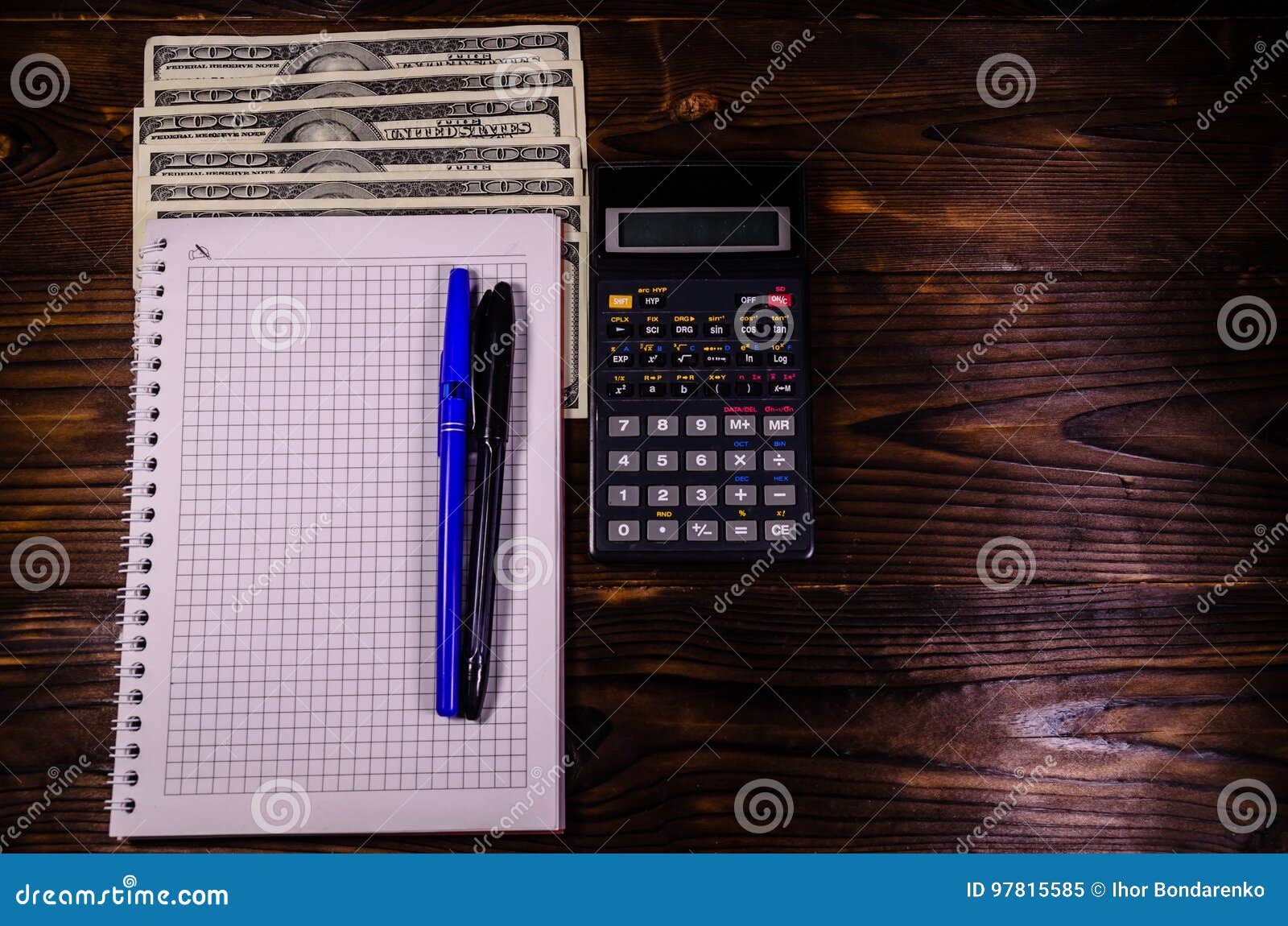 Notepad, Pen, Calculator and Dollar Bills on Wooden Table. Top V Stock