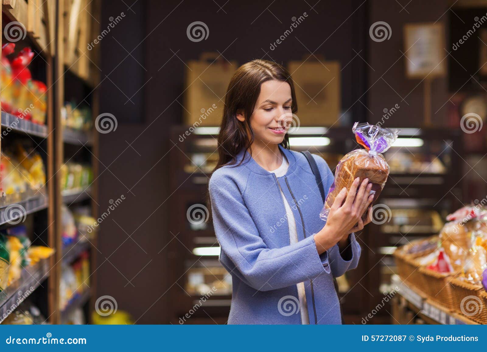 Nourriture de choix et de achat de femme heureuse sur le marché. Vente, achats, consommationisme et concept de personnes - jeune femme heureuse choisissant et lisant le label sur le pain sur le marché