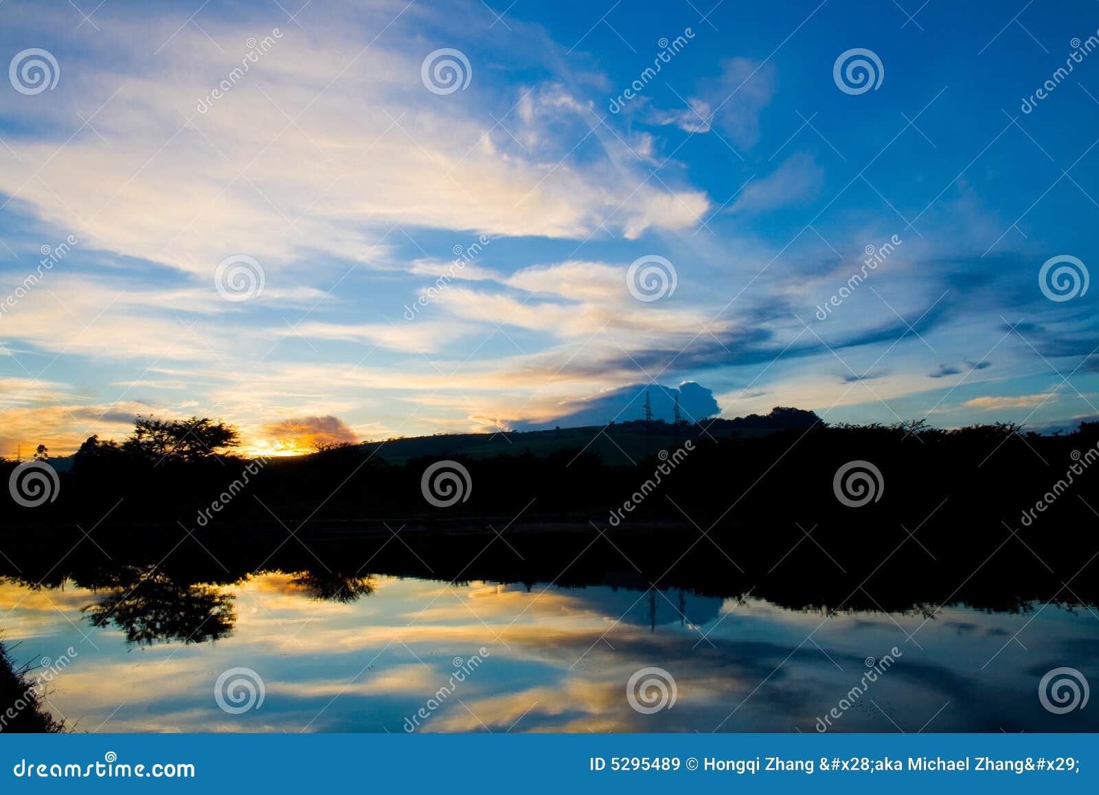 Le nubi variopinte riflettono sulla superficie dell'acqua del lago all'alba.