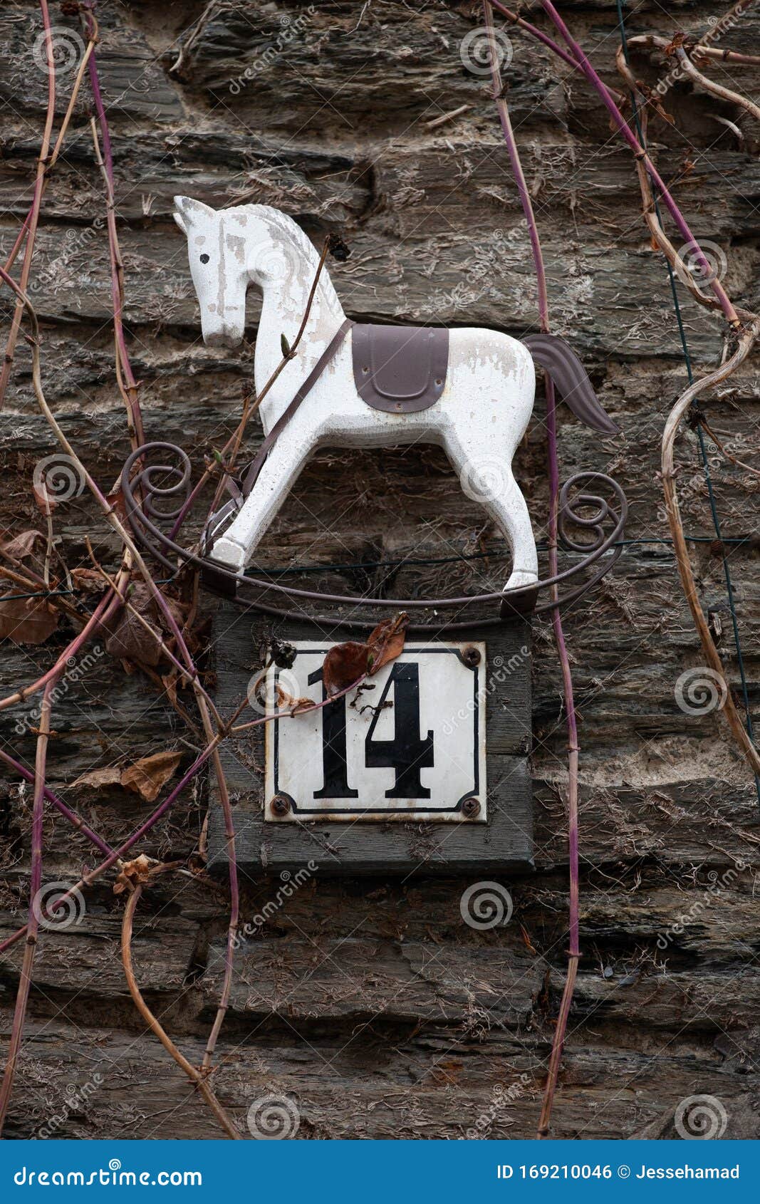 number 14 house number sign with small rocking horse decoration on stone wall