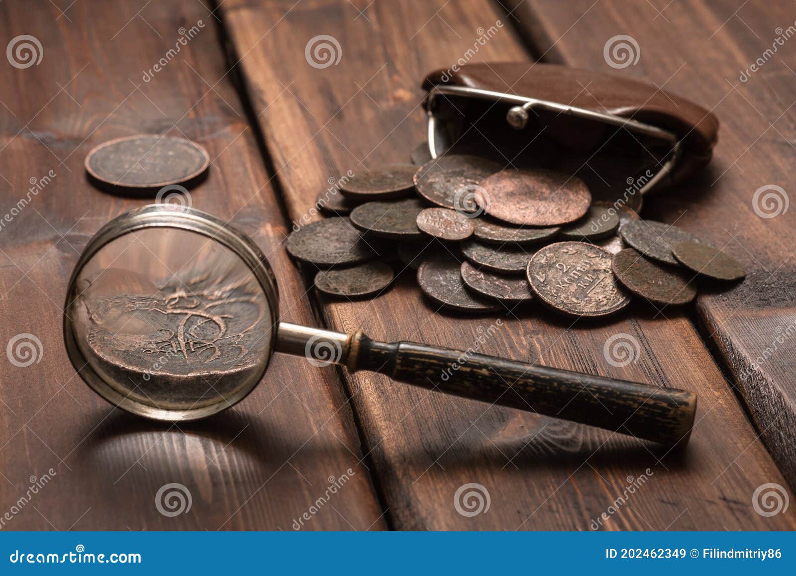 Different old collector's coins with a magnifying glass, blurred