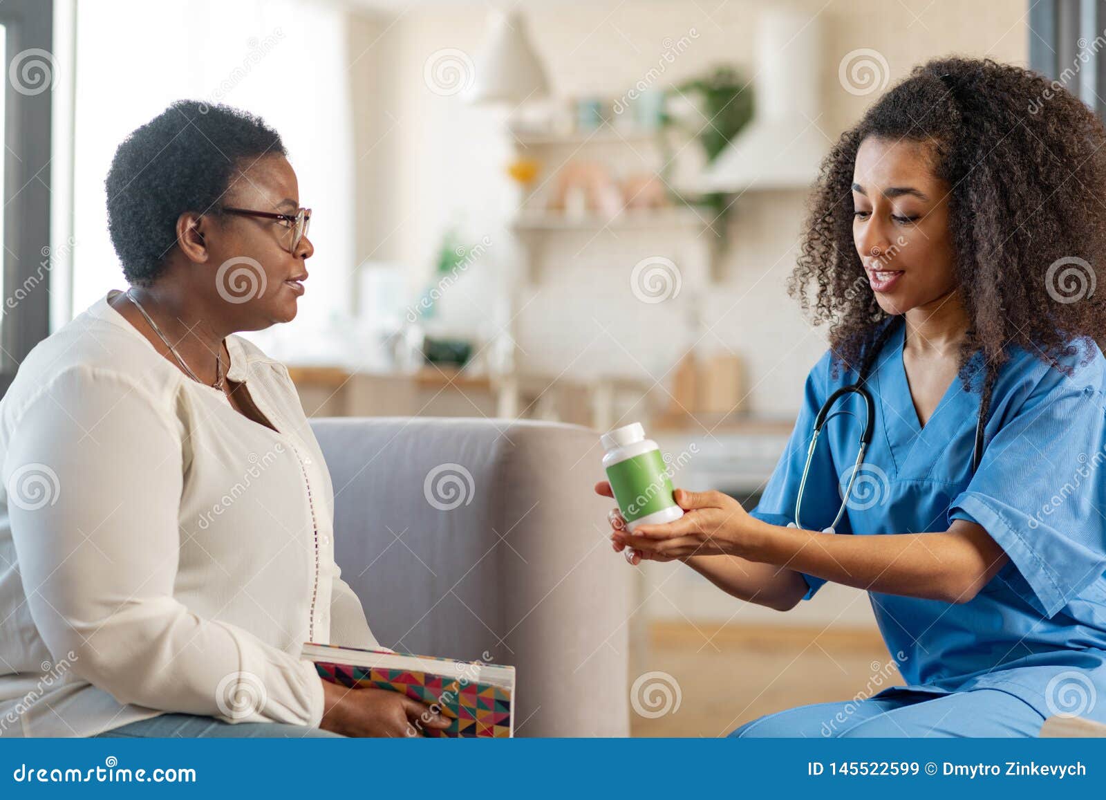 Dark Skinned Woman With Short Hair Talking To Nurse Bringing