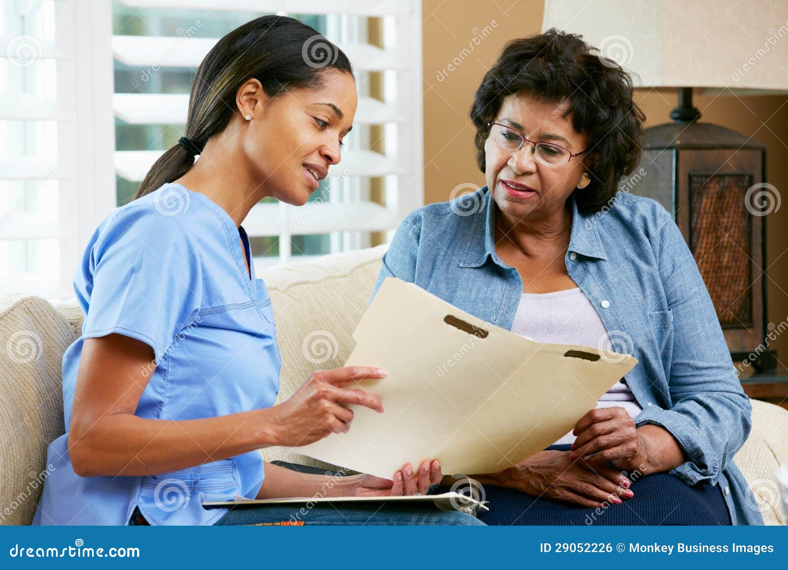 nurse discussing records with senior female patient during home