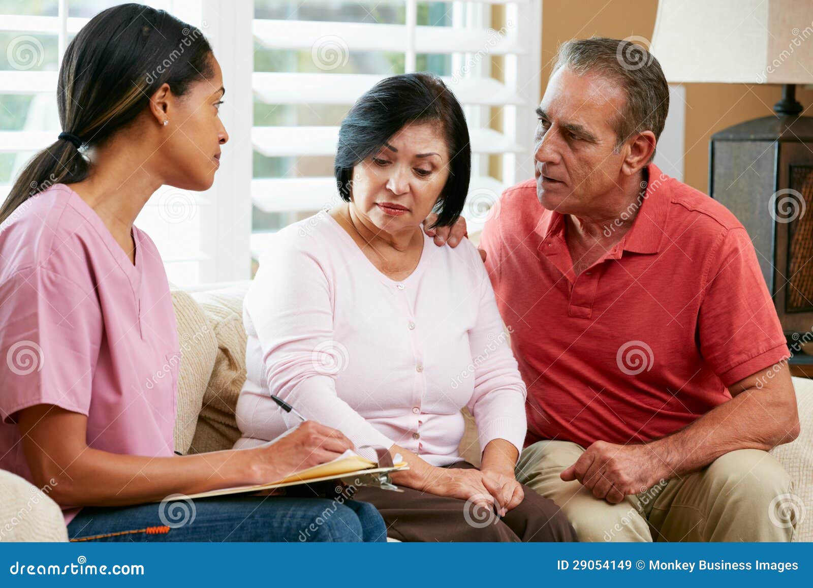 nurse making notes during home visit with senior couple