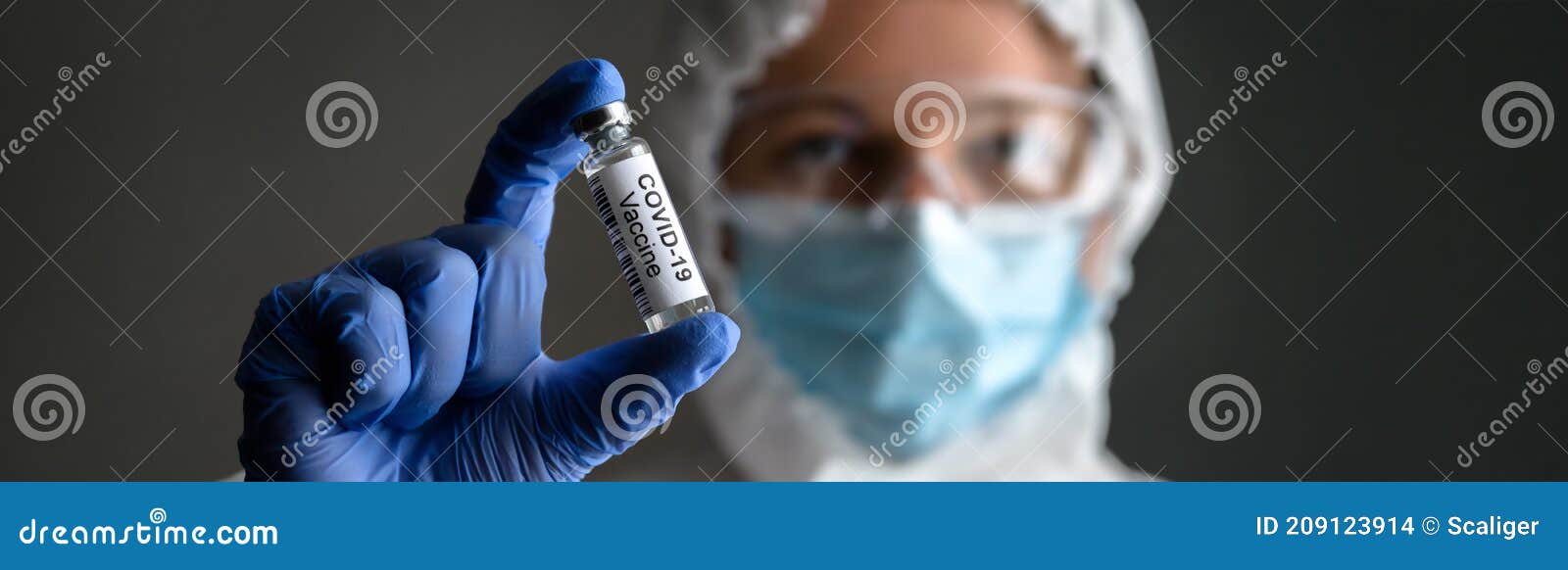 nurse in medical ppe suit holds bottle with vaccine for covid-19 cure