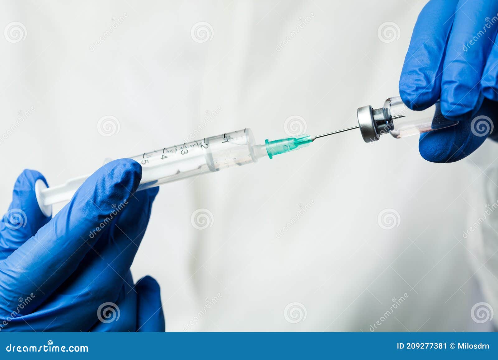 nurse of nhs medical lab technician inserting syringe needle into glass vial bottle