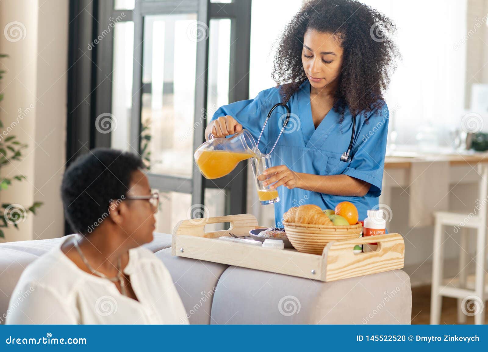 Nurse Pouring Some Orange Juice for Lady Living in Nursing House Stock