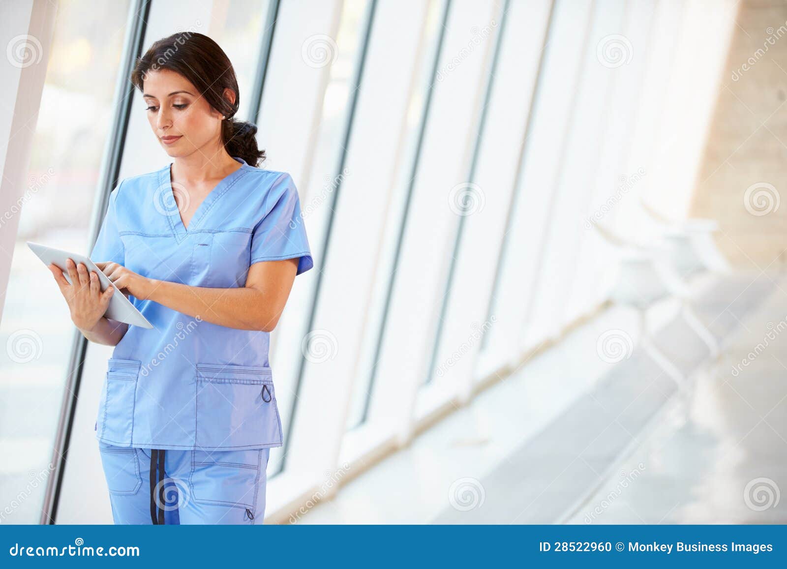 nurse using digital tablet in corridor of modern hospital