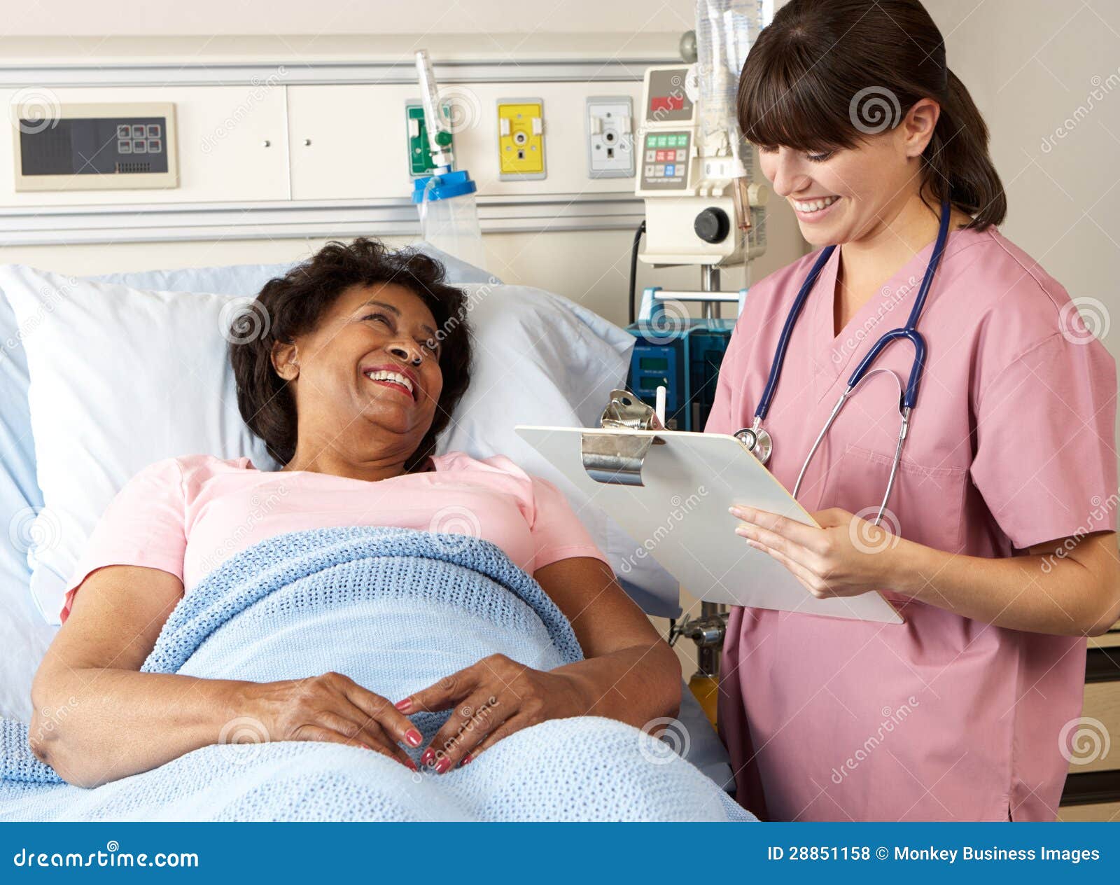 nurse visiting senior female patient on ward