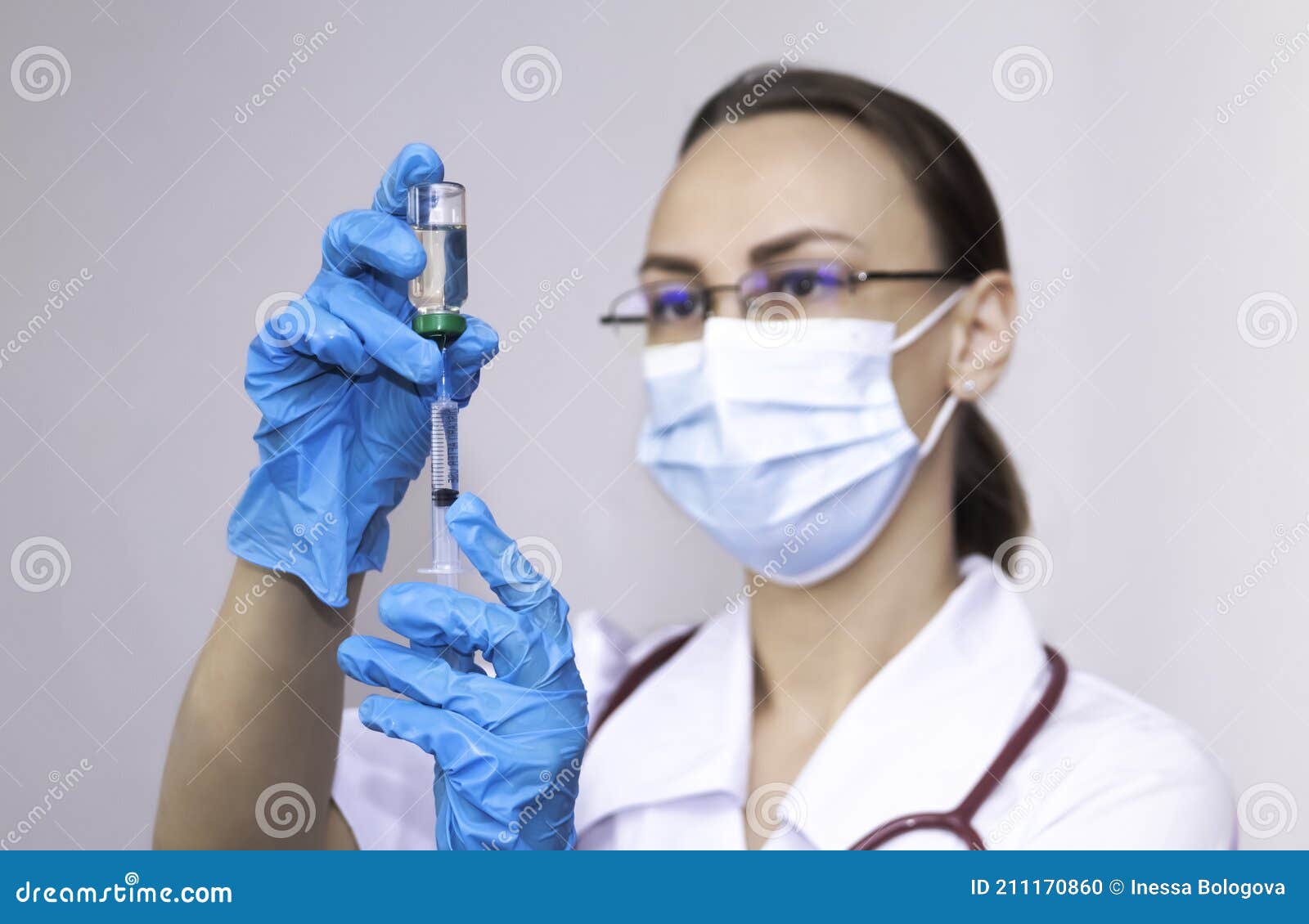 a nurse wearing protective gloves and a mask dials a vaccine into a syringe, the concept of vaccinating the population
