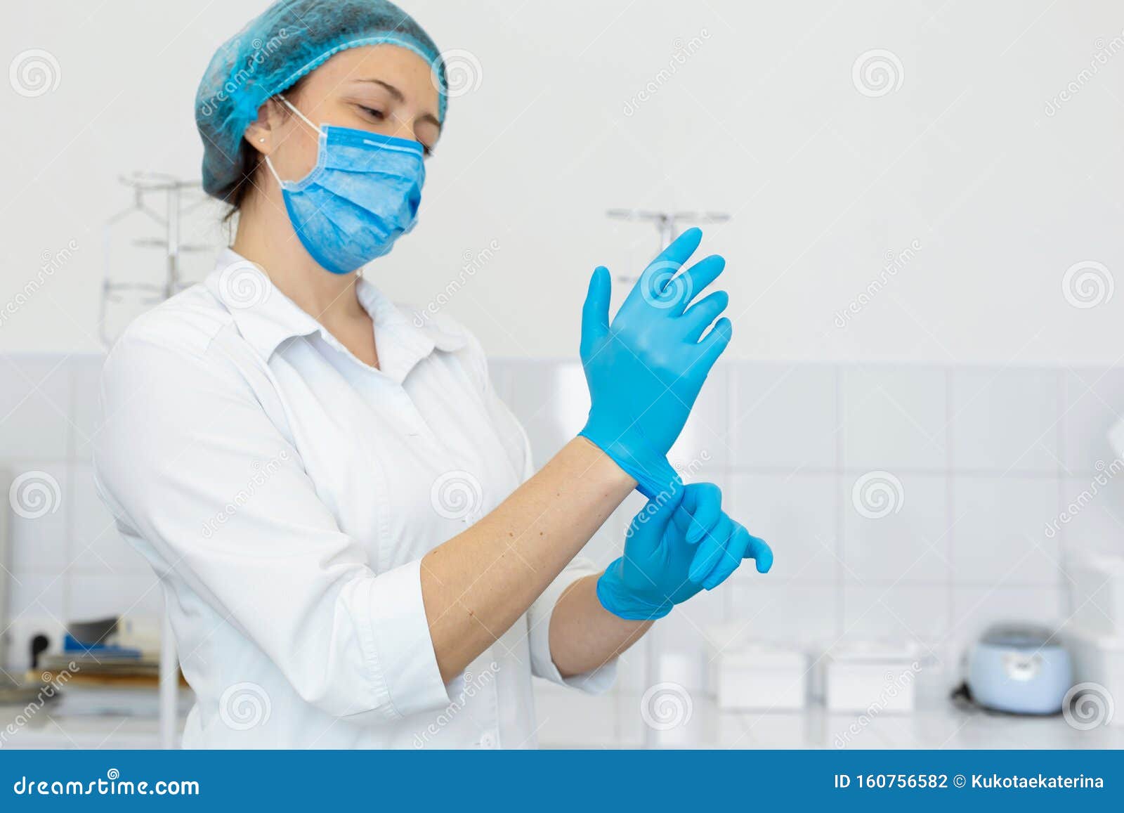 a nurse in a white coat puts on rubber gloves before a medical procedure in a bright handling room