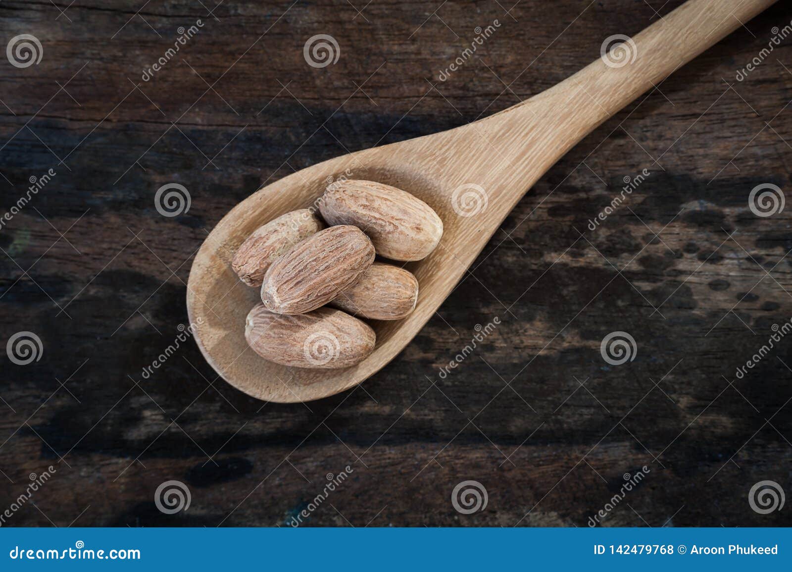 nutmeg on wooden spoon over wooden background.