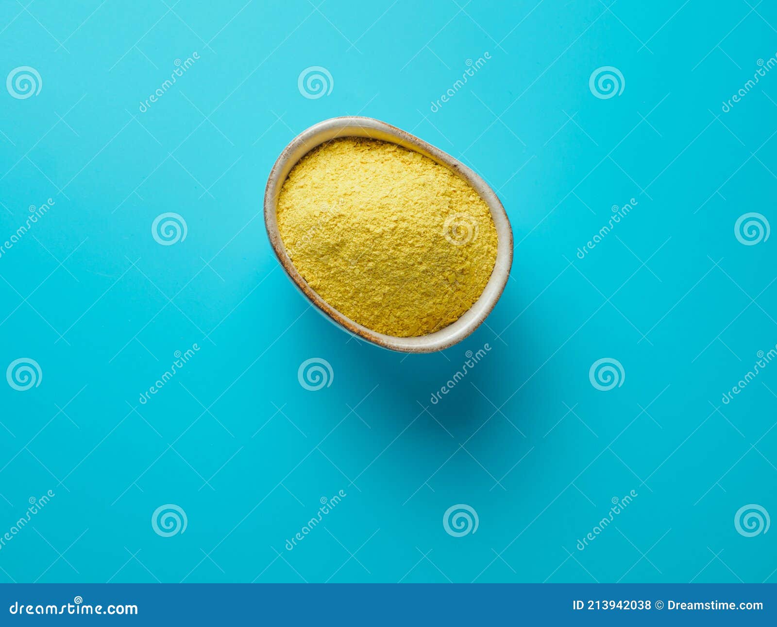 nutritional yeast in white bowl on blue background.