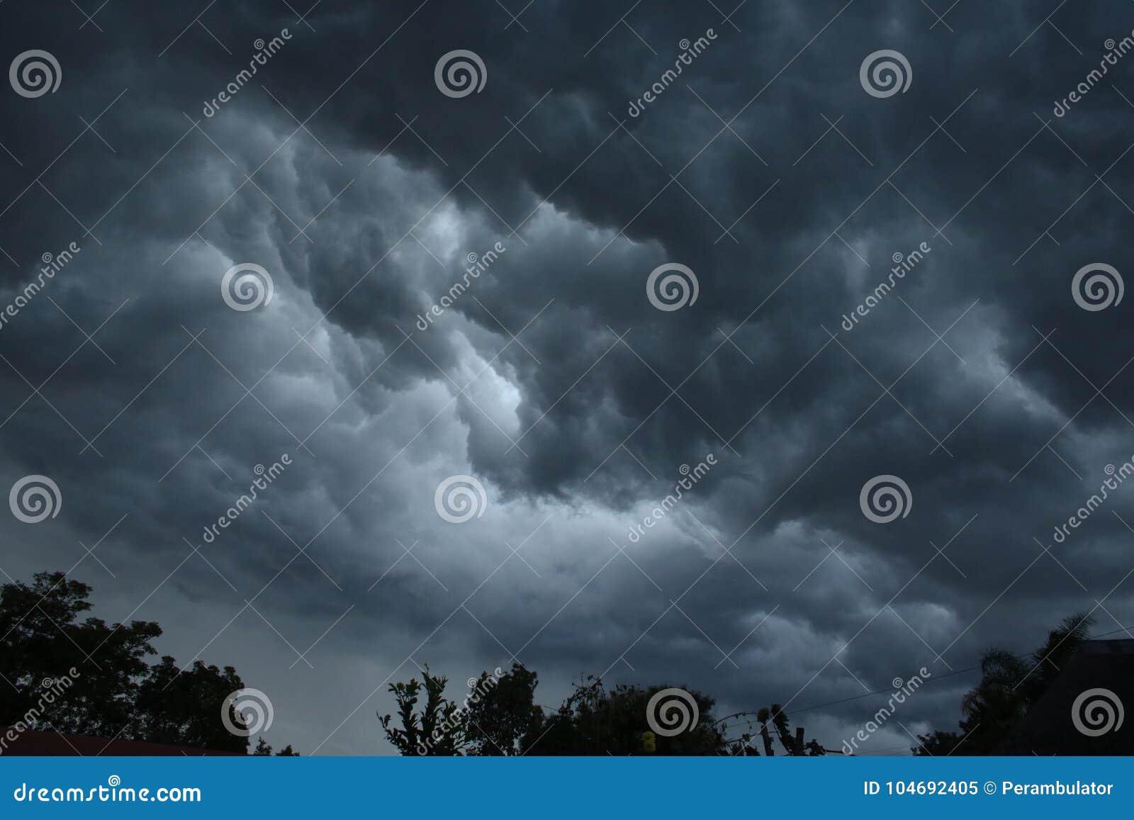 NUVENS DE TEMPESTADE ACIMA DAS ÁRVORES. A nuvem sinistra da obscuridade situou o ponto baixo no céu com o remendo da luz