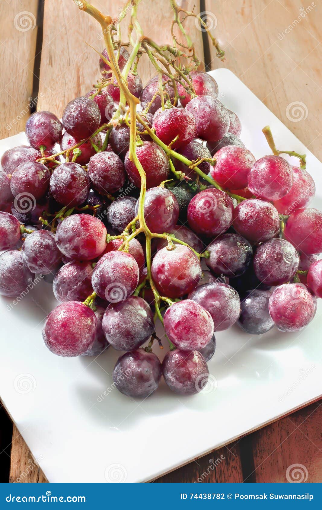 Nya röda druvor på den vita maträtten och trätabellen är en sund mat