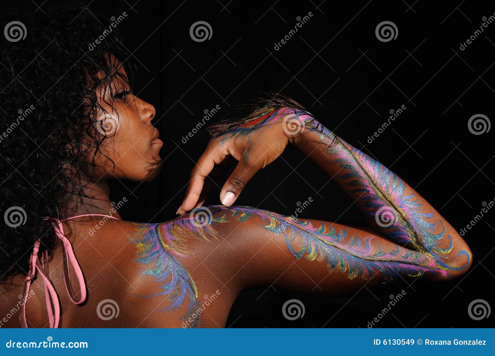 O braço fêmea com bodypaint. O retrato da menina africana na moda nova com bodypaint o desenho em seu braço - isolado no preto