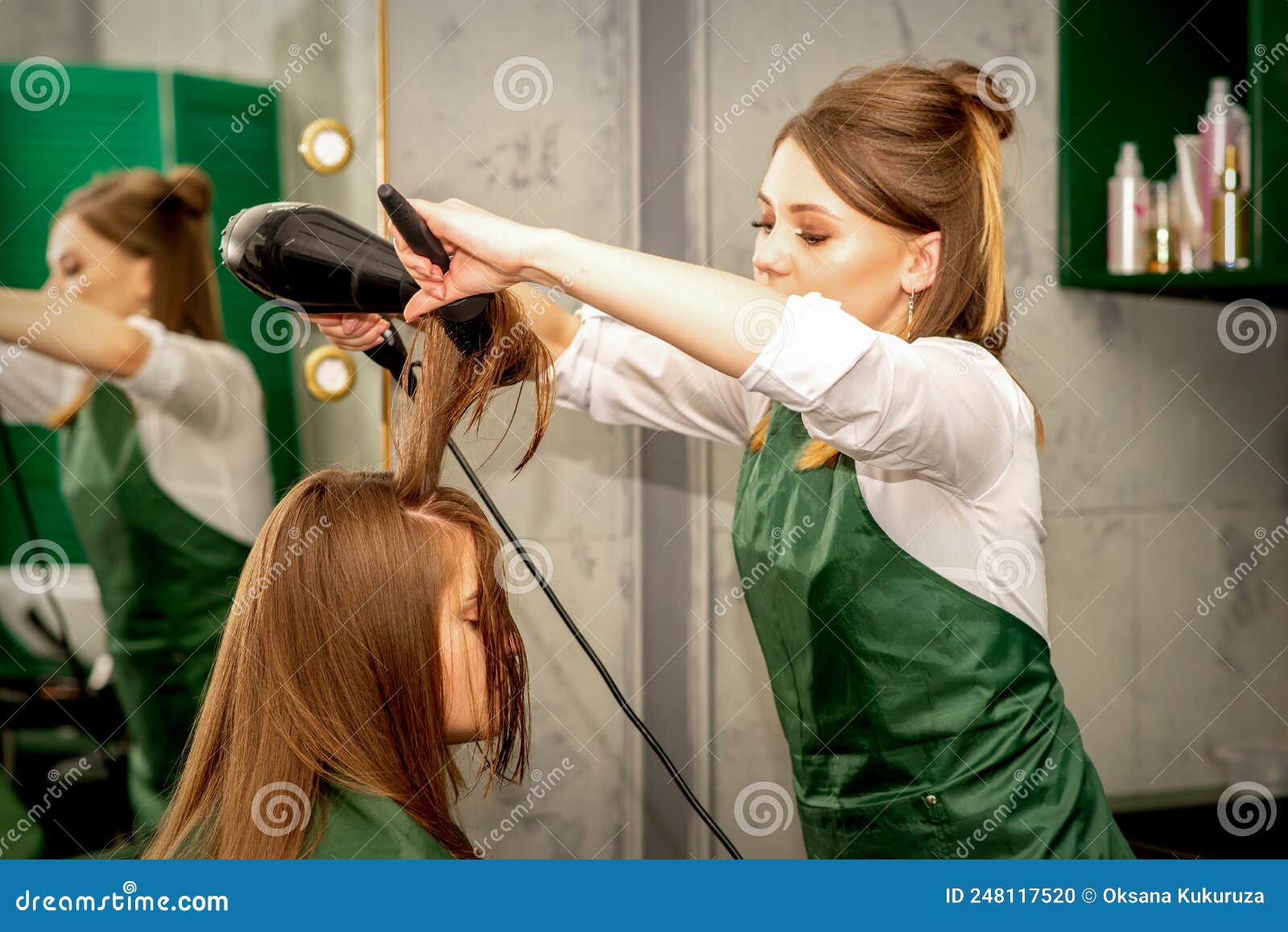 Cabeleireiro seca e modela o cabelo com um secador de cabelo no