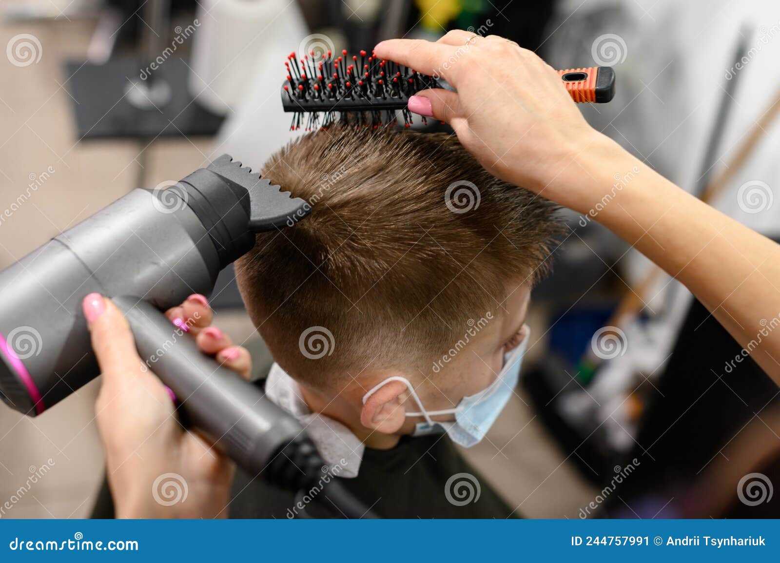 Cabeleireiro seca e modela o cabelo com um secador de cabelo no salão de  beleza