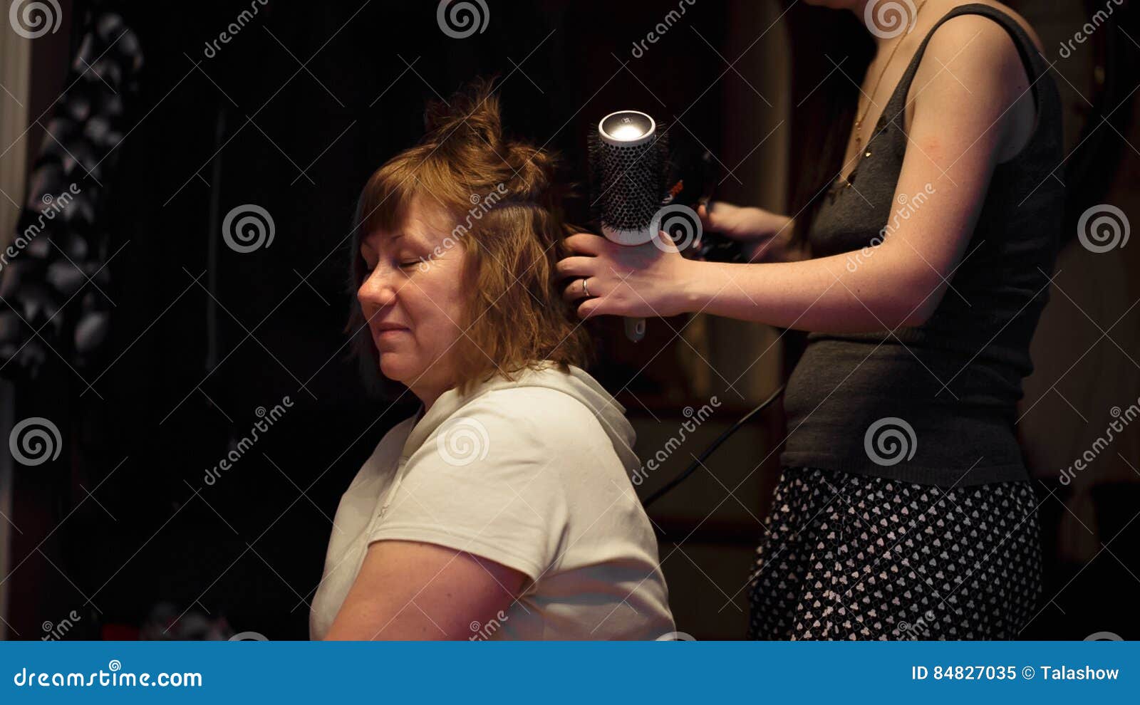 Cabeleireiro seca o cabelo com uma mulher de secador de cabelo no