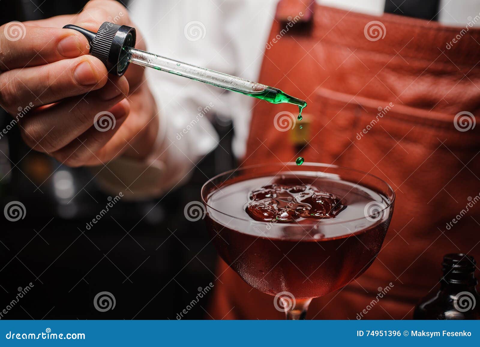 O empregado de bar perito está fazendo o cocktail e está terminando-o acima deixando cair amargo verde