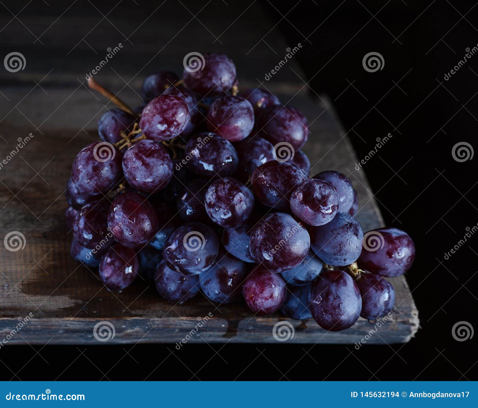 O grupo de uvas encontra-se em uma tabela de madeira. Uvas azuis na tabela