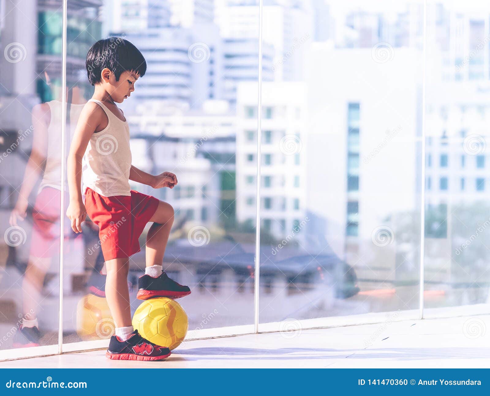 Menino jogador de futebol está pisando na bola na sala