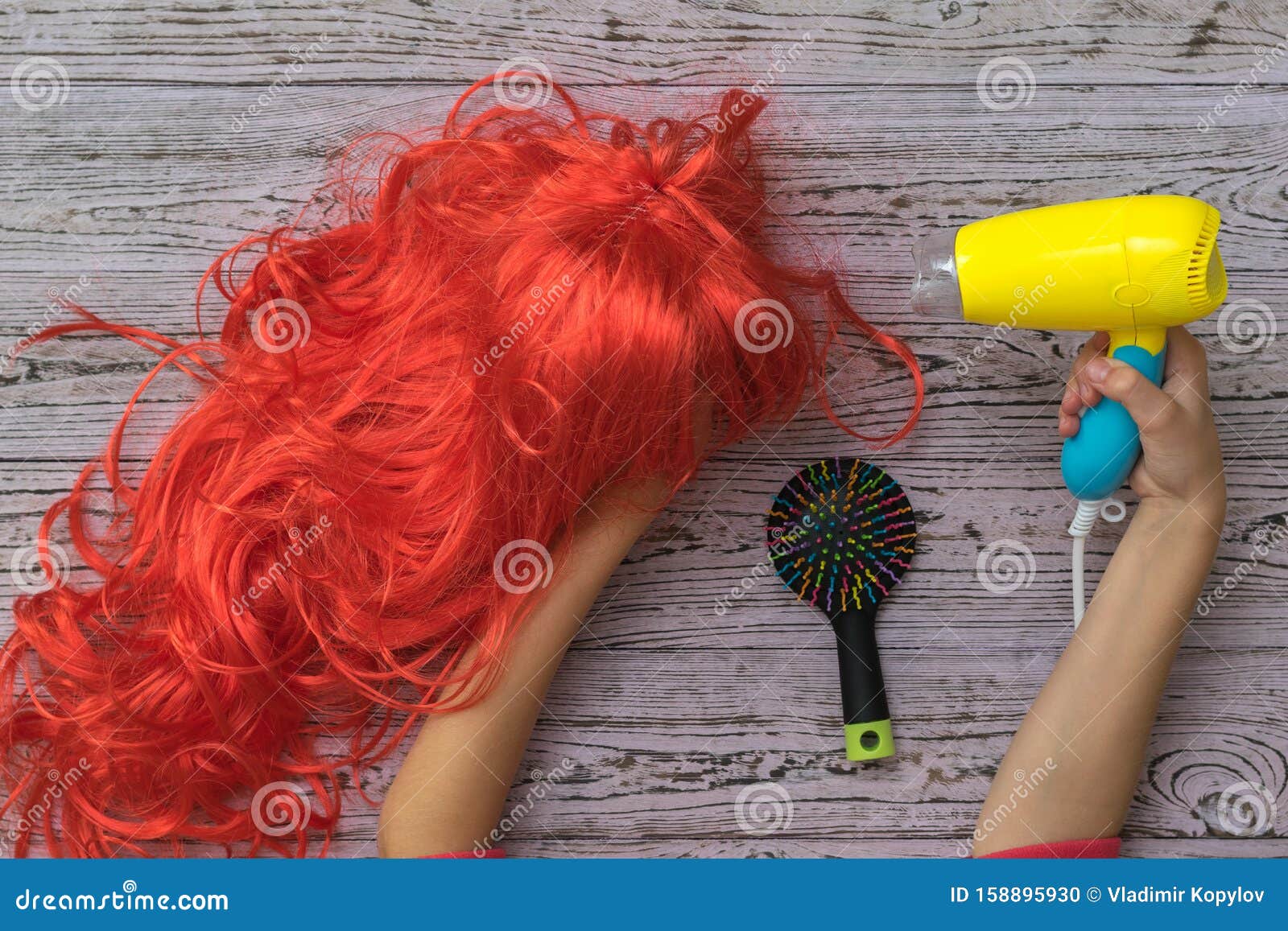 Secador de cabelo preto na mão de uma mulher em um fundo rosa