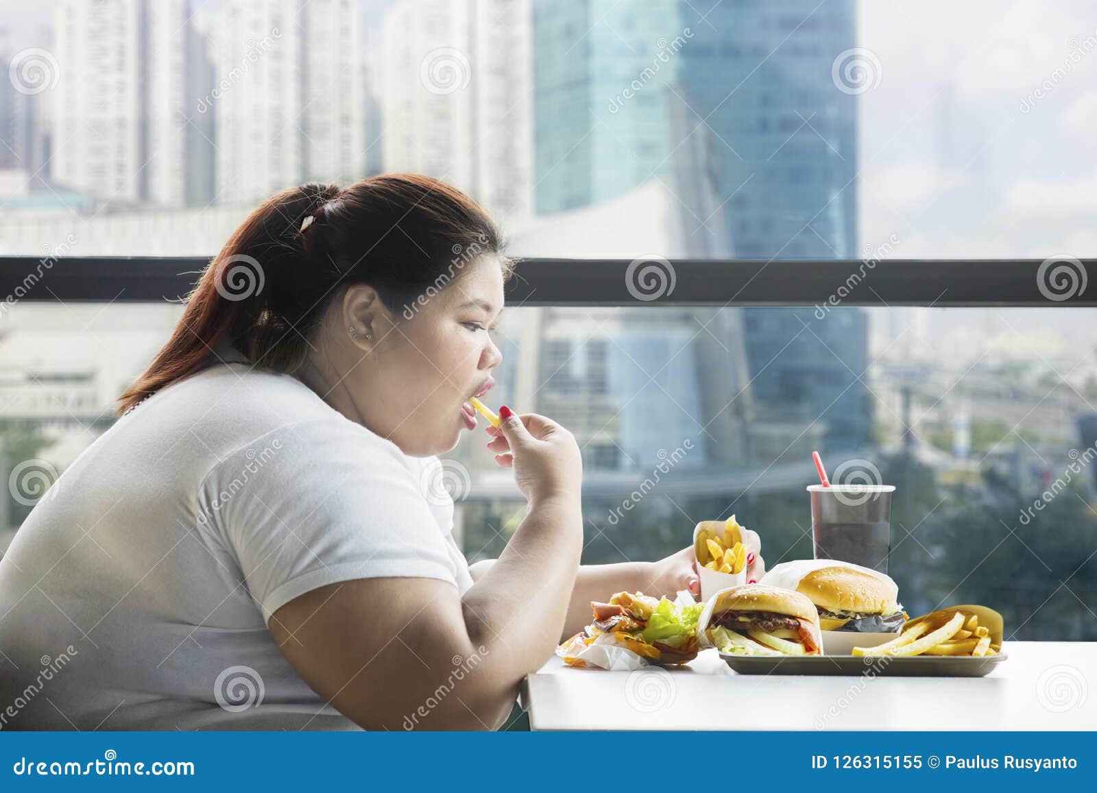 obese woman eating french fries in the restaurant