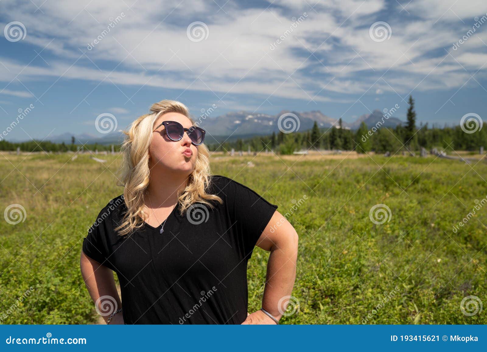 obnoxious blonde woman does a duck face with pouting lips, hands on hips, in glacier national park, near polebridge, montana, in a