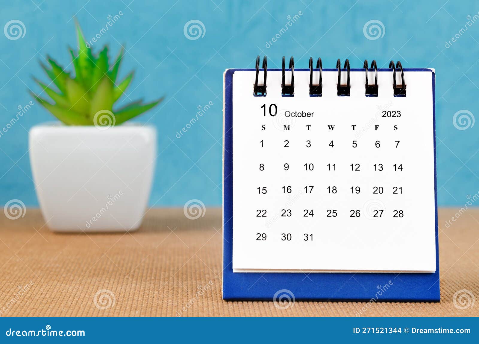 the october 2023 desk calendar wiht platn pot on blue color background