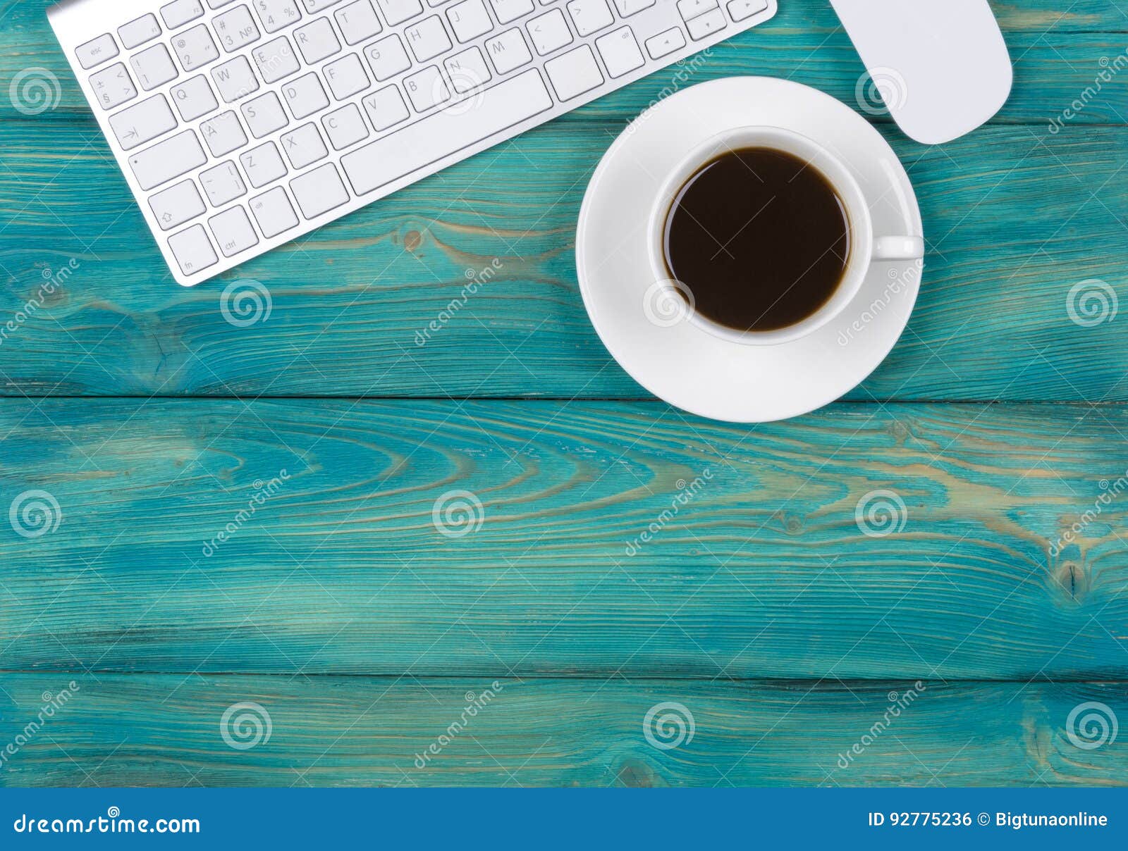 Office desk with copy space. Digital devices wireless keyboard and mouse on red wooden table with cup of coffee, top view.