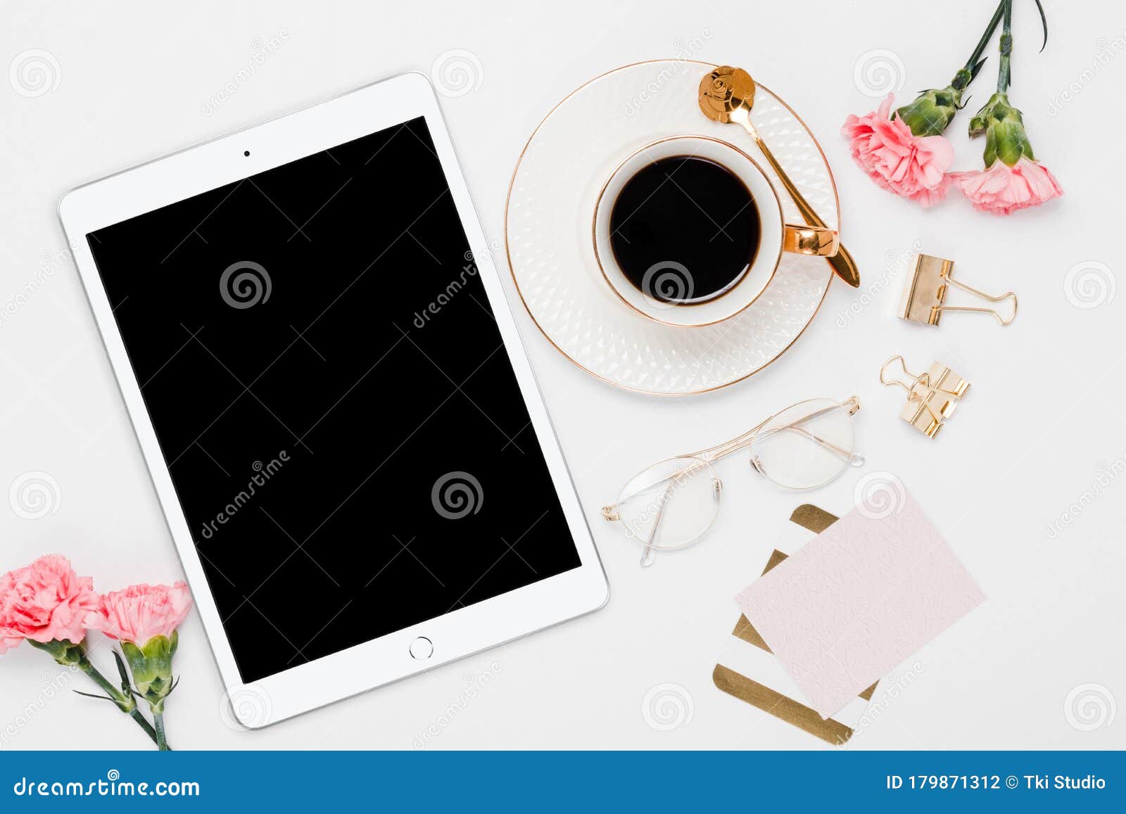 ipad with gold desk accessories and pink flowers in a white background