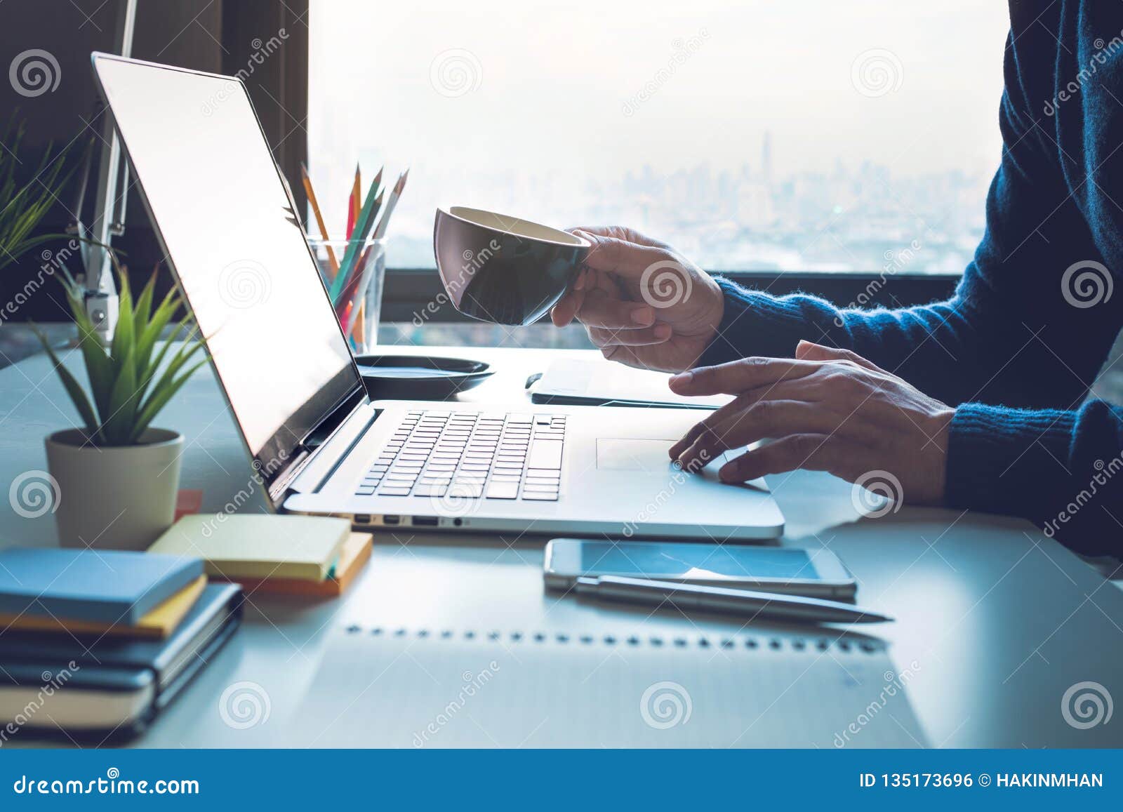 office life  with person drinking coffee and using computer laptop on window