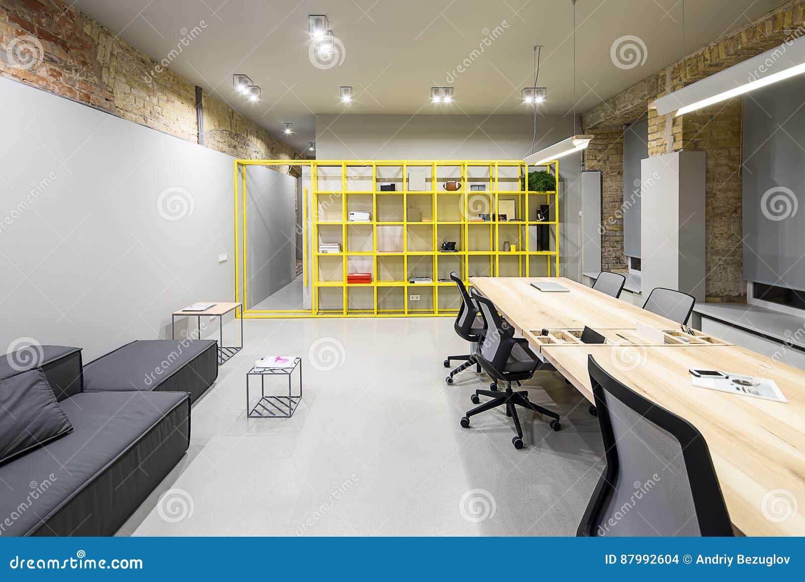 Dark Gray Opened Wall Shelf loft style office with gray and brick walls there are glowing lamps dark sofa with pillow wooden tables with chairs small metal tables metal yellow