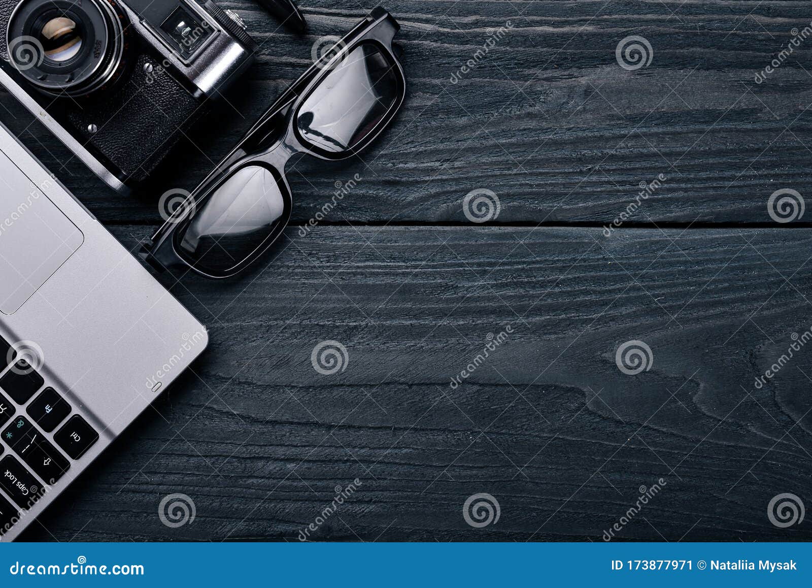 office work space with camera, notebook, eyepieces, and pen. on a wooden surface. top view.