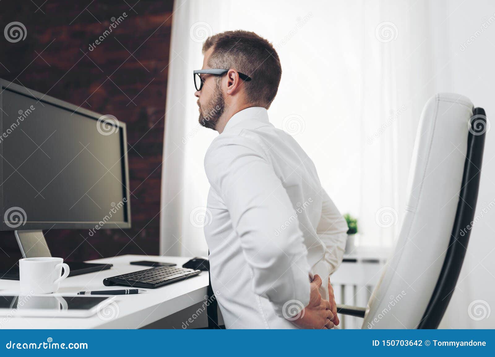 Office Worker with Pain from Sitting at Desk All Day Stock Photo