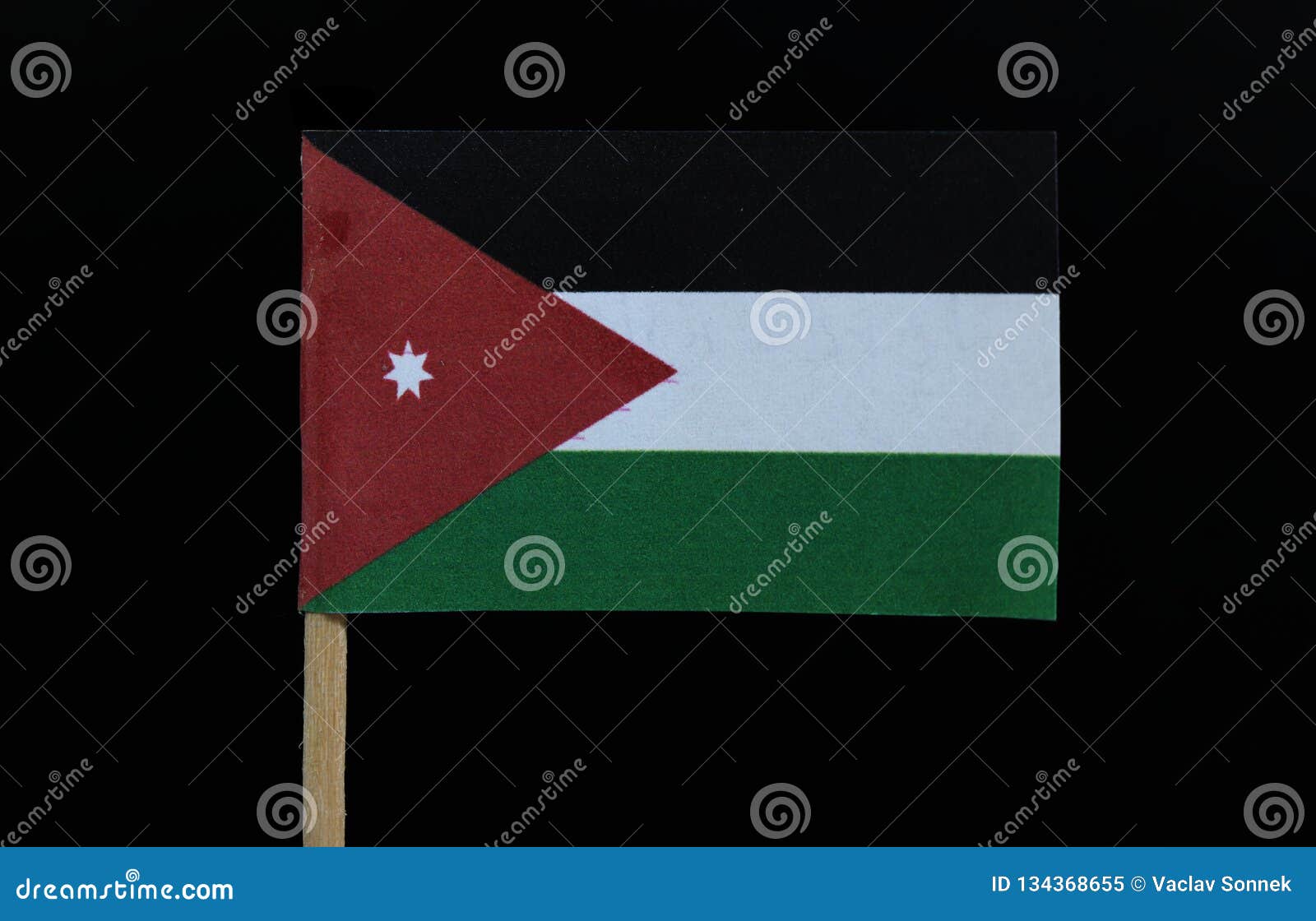 a official and unique flag of jordan on toothpick on black background. a horizontal triband of black, white and green; with a red