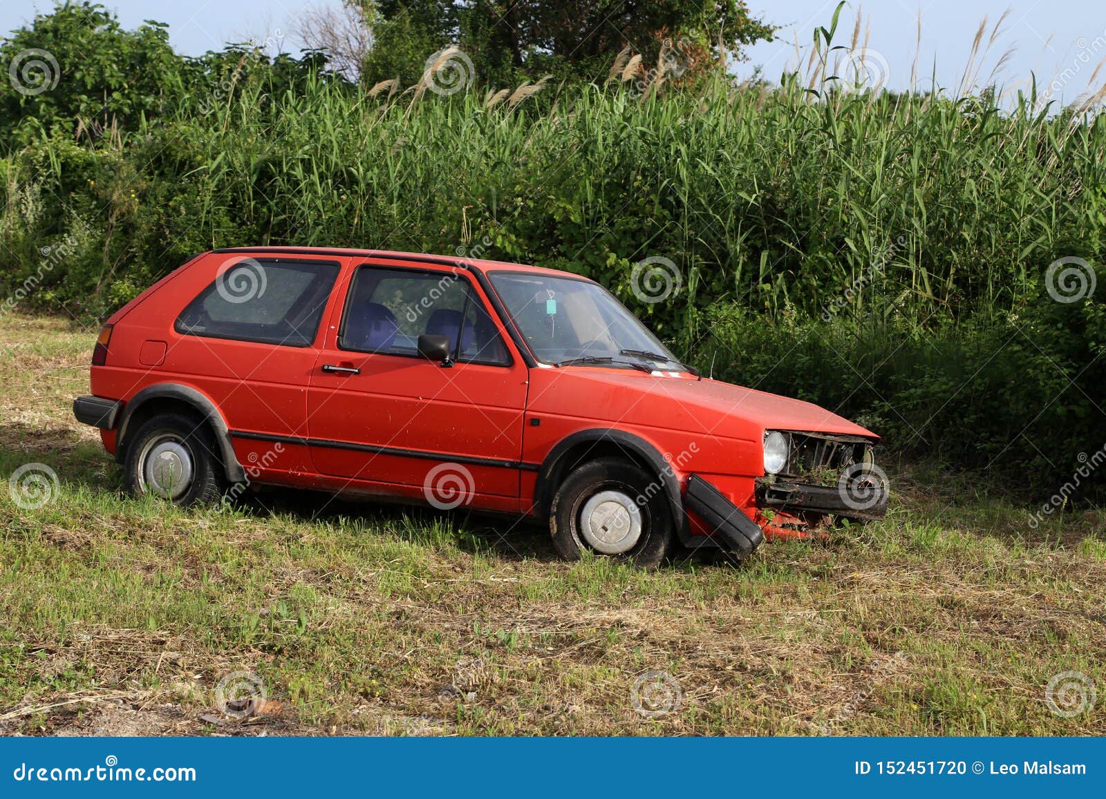 an old abandoned car rusts by the road