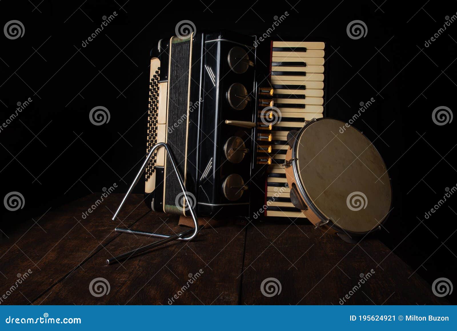 old accordion, tambourine and triangle on rustic wooden surface with black background and low key lighting, selective focus