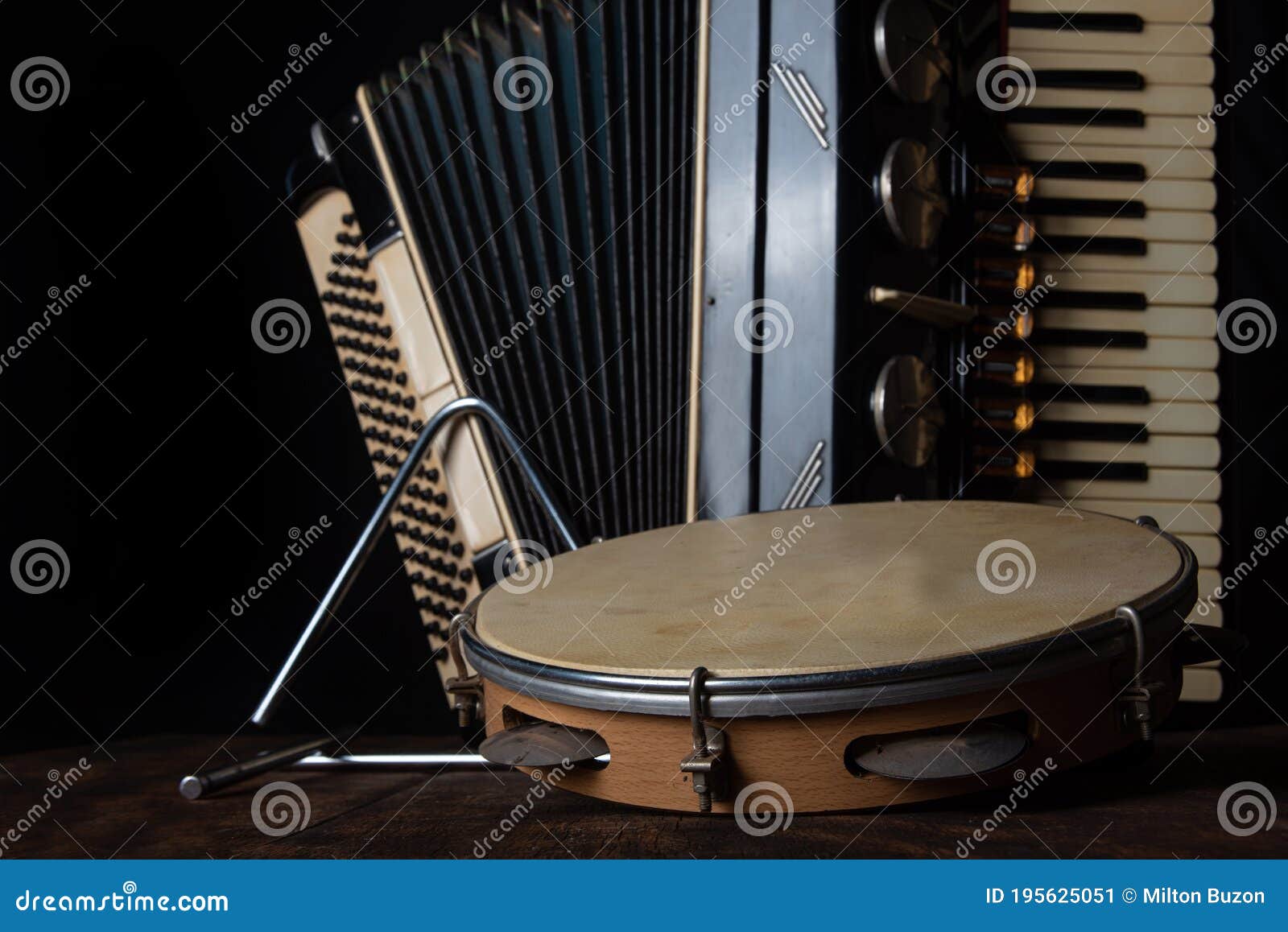 old accordion, tambourine and triangle on rustic wooden surface with black background and low key lighting, selective focus