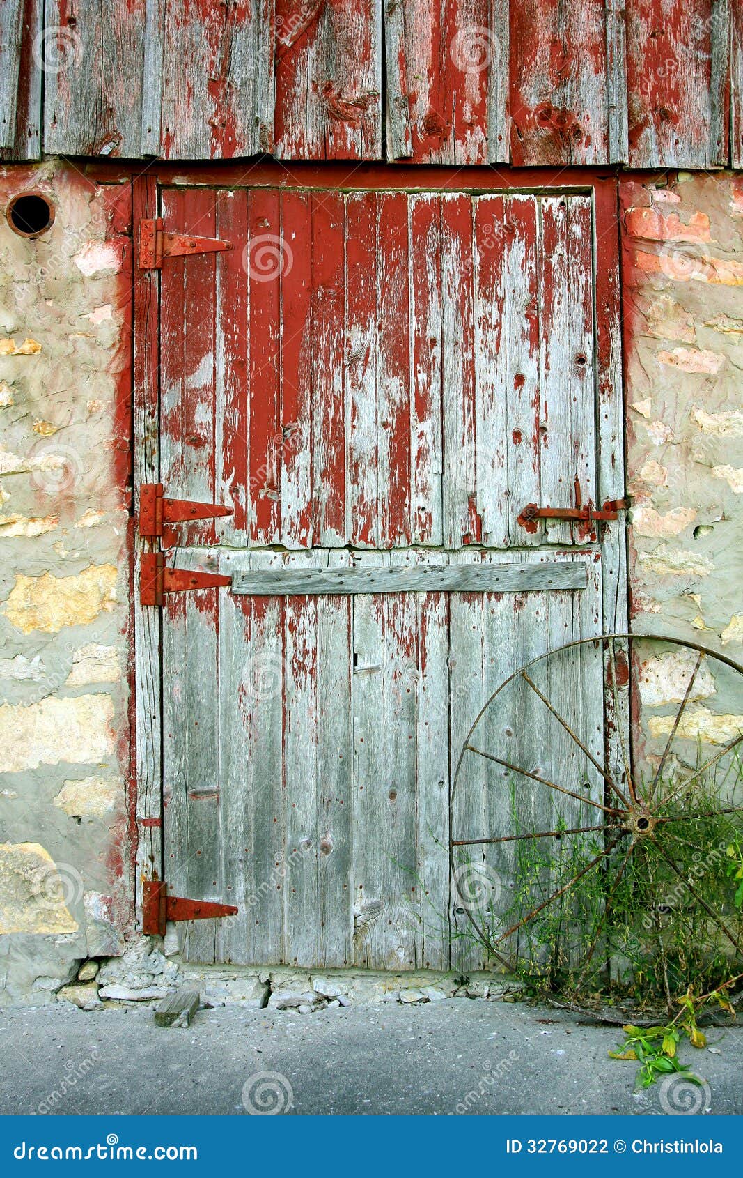 rustic old barn door with peeling red paint, stone walls, and an 