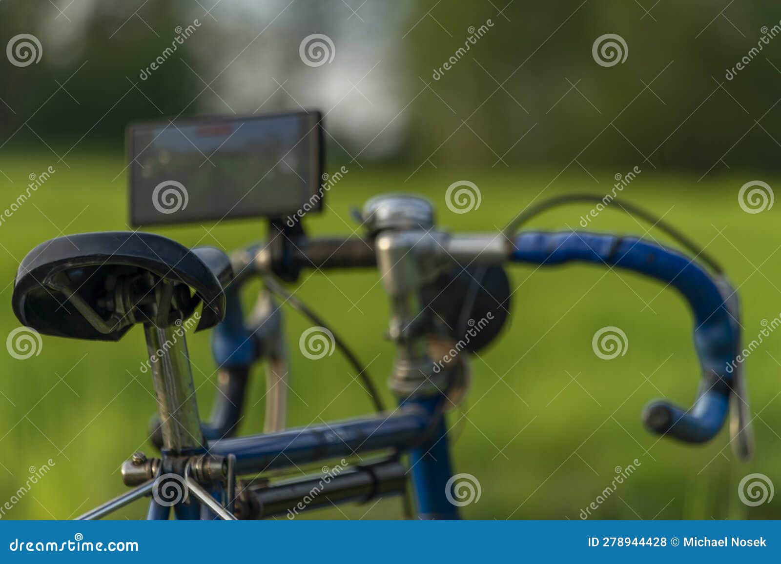 old bicycle with very modern mobile phone on handlebar on spring color meadow