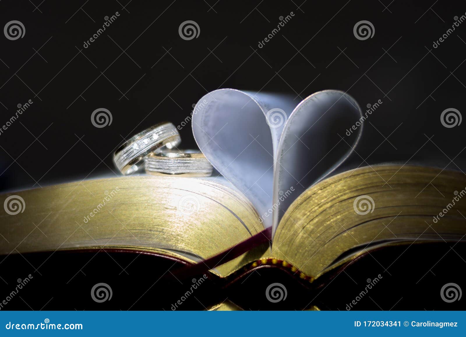 old book with heart-d pages. ring between pages, black background.