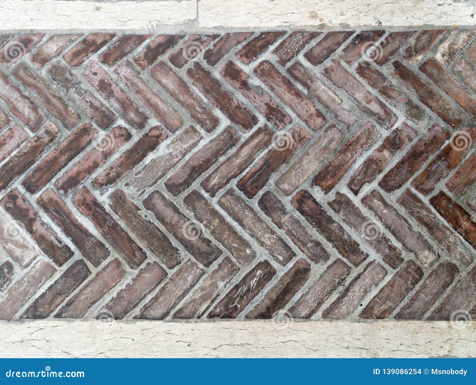 Old Brick Pavement in a Herringbone Style for Background Stock Photo