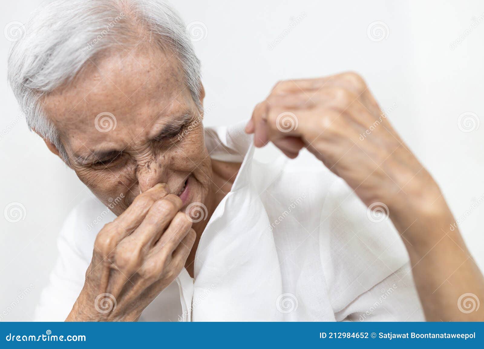 old elderly people is sniffing shirt smell moldy,closing nose with the disgusting,intolerable smell,dirty laundry,unclean washing,