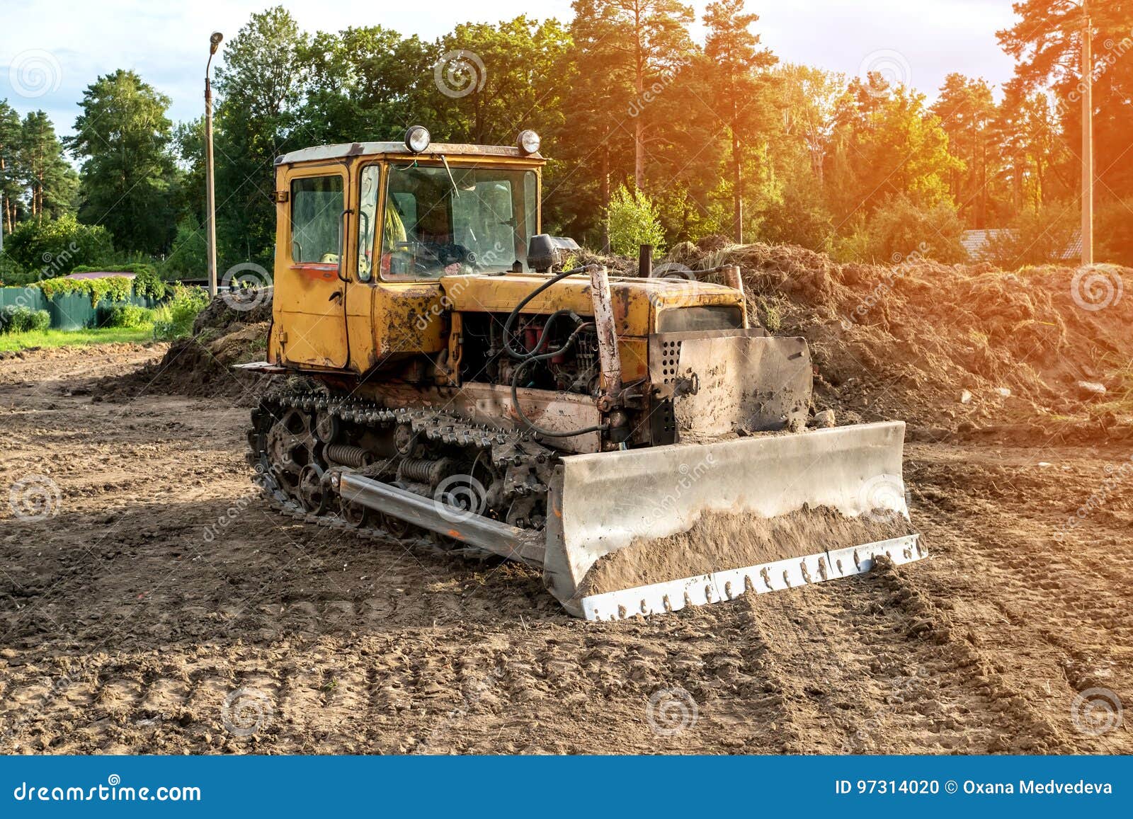 Old Excavator Working Clearing Land at Sunset of a Sunny Day. Stock
