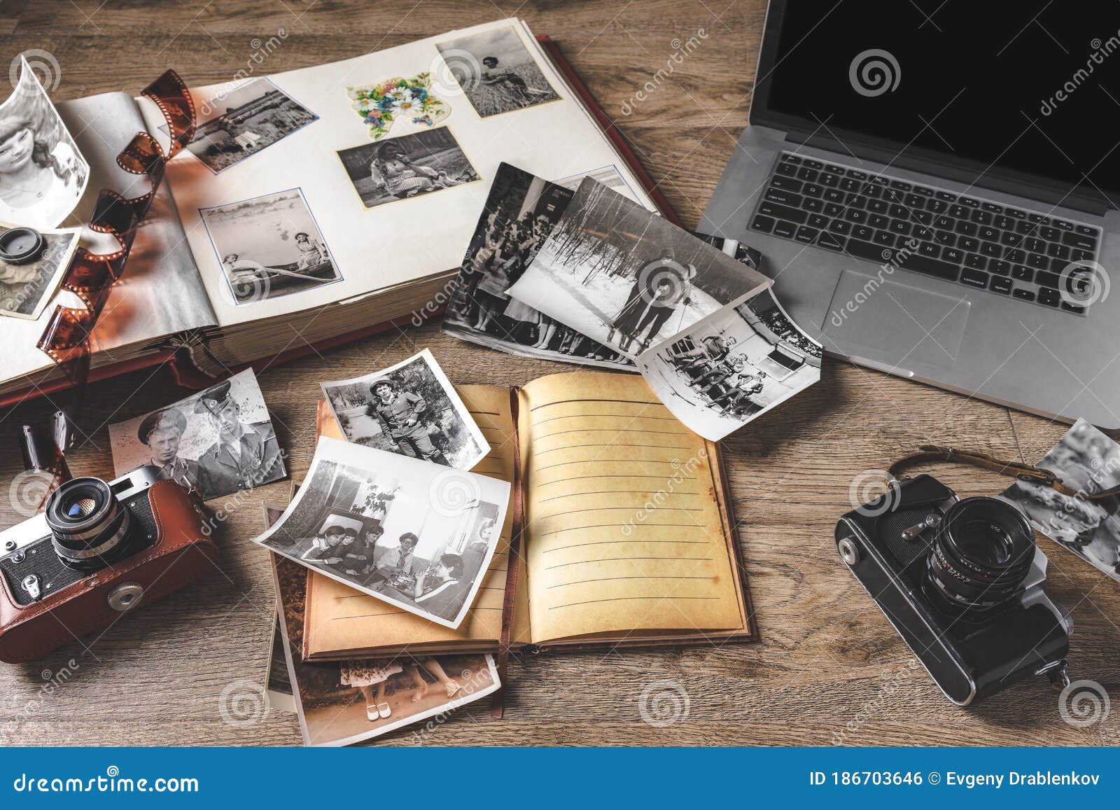 old family photos and album on wooden background. vintage pictures, camera, notepad and modern notebook