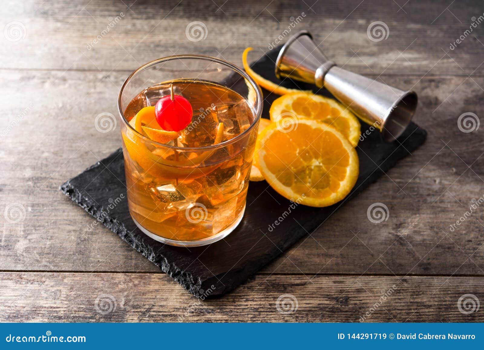old fashioned cocktail with orange and cherry on wooden table