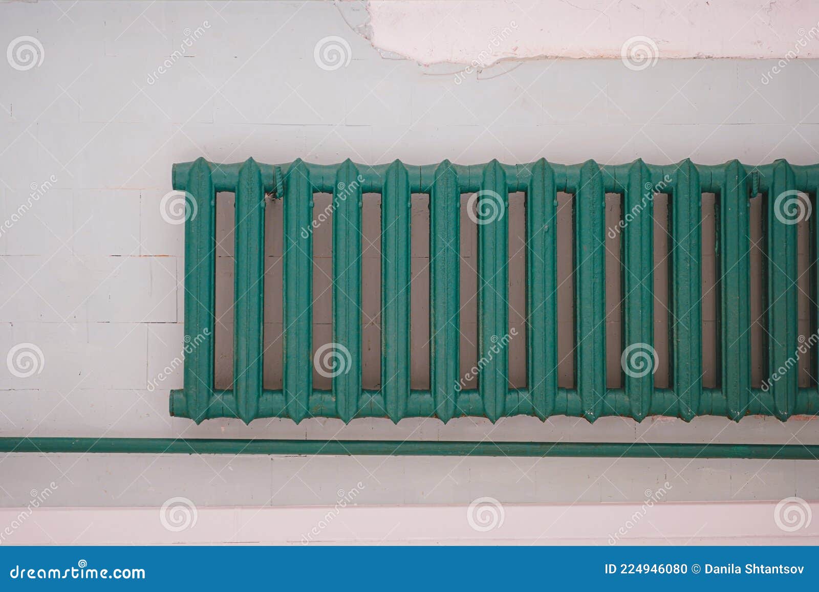Oldfashioned Green Heating Radiator on a Grey Tile Wall. Indoor